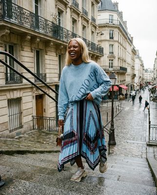 a woman in a blue sweater is walking down the street