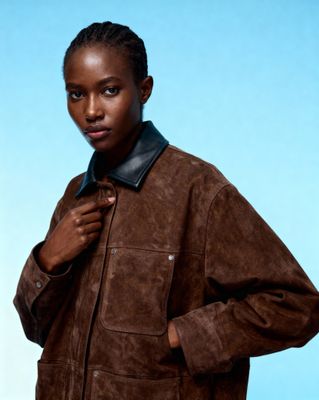 a woman in a brown jacket is posing for a picture