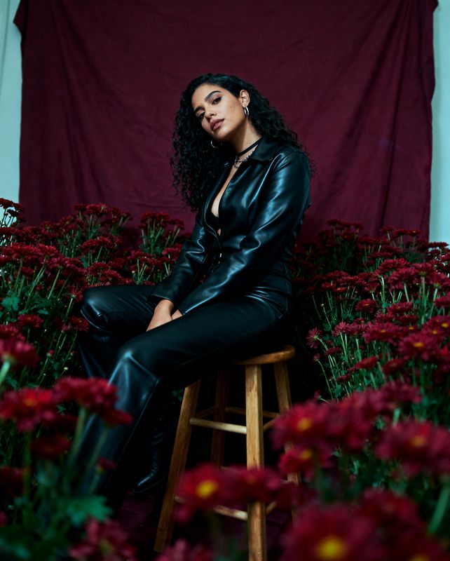 a woman sitting on a stool in front of flowers