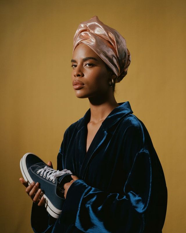 a woman in a turban holding a pair of sneakers