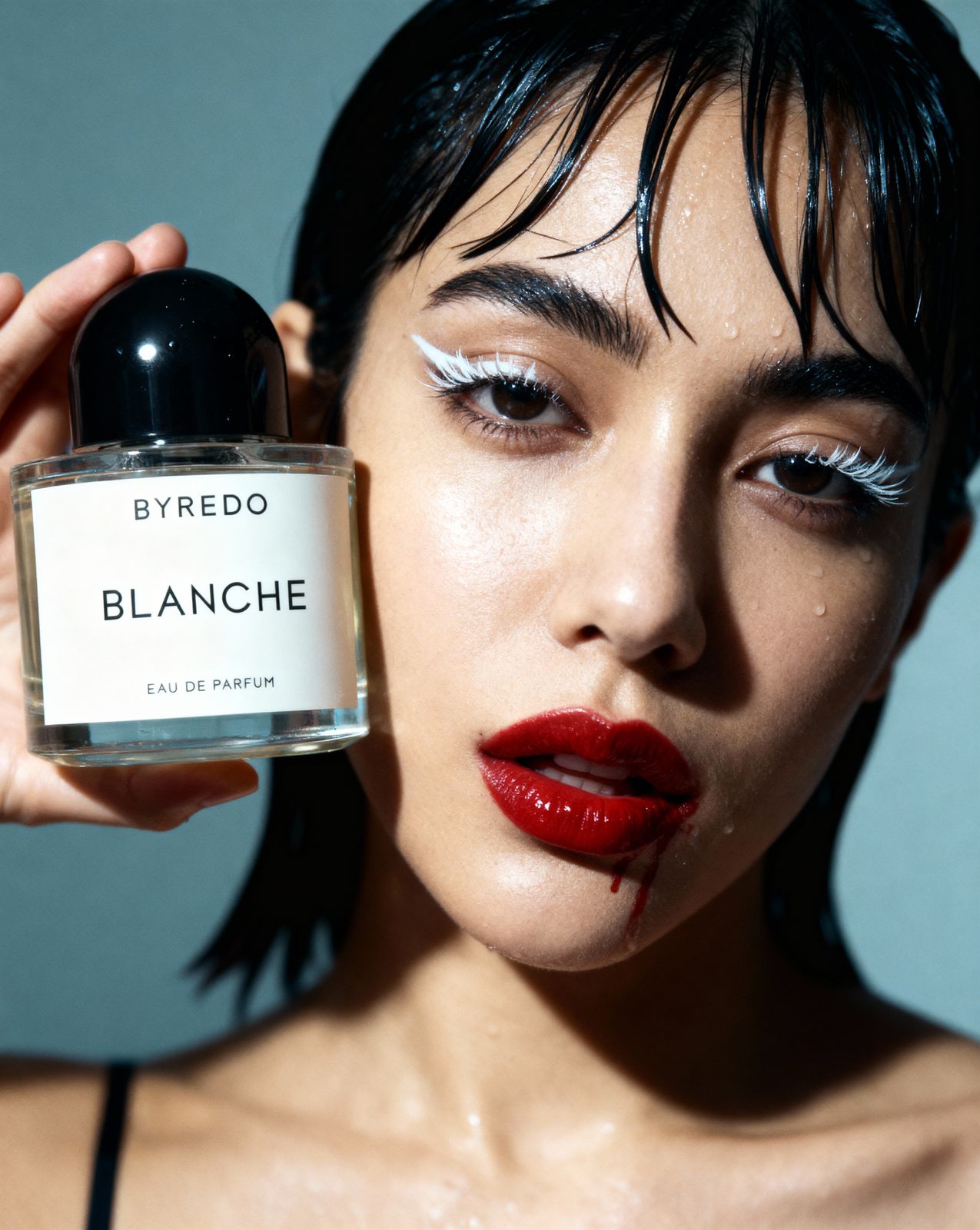 a woman holding a bottle of perfume in front of her face