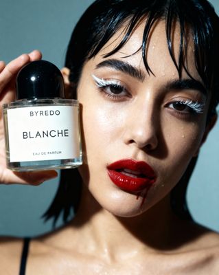 a woman holding a bottle of perfume in front of her face