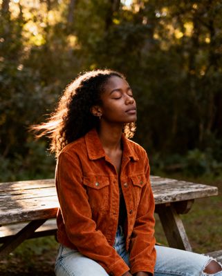 a woman sitting on a bench with her eyes closed
