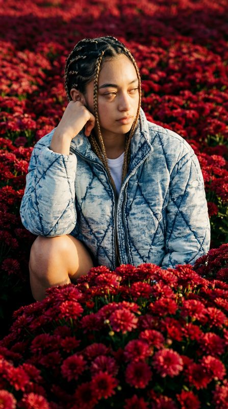 a woman sitting in a field of red flowers