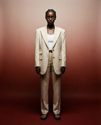 a man in a suit standing in front of a red wall