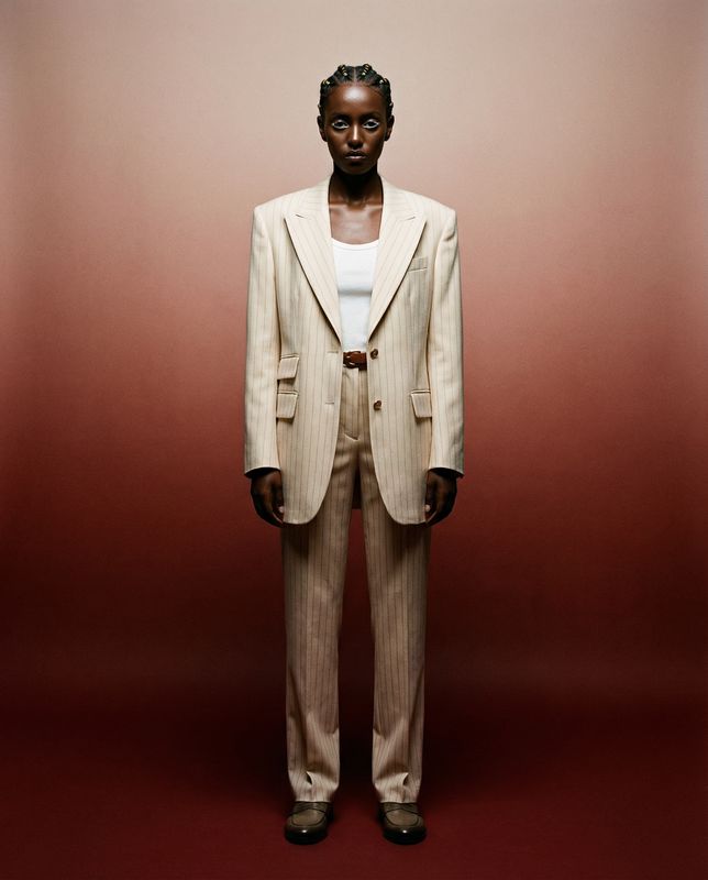 a man in a suit standing in front of a red wall