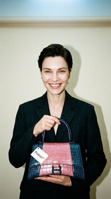 a woman holding a purse with a name tag on it