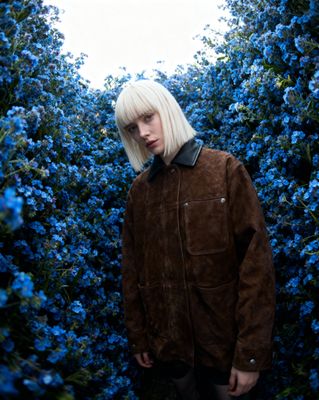 a woman with blonde hair standing in front of blue flowers