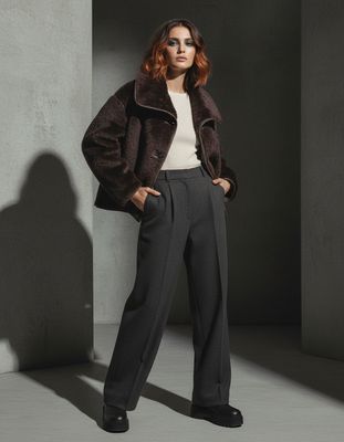 a woman standing in a room wearing a coat and pants