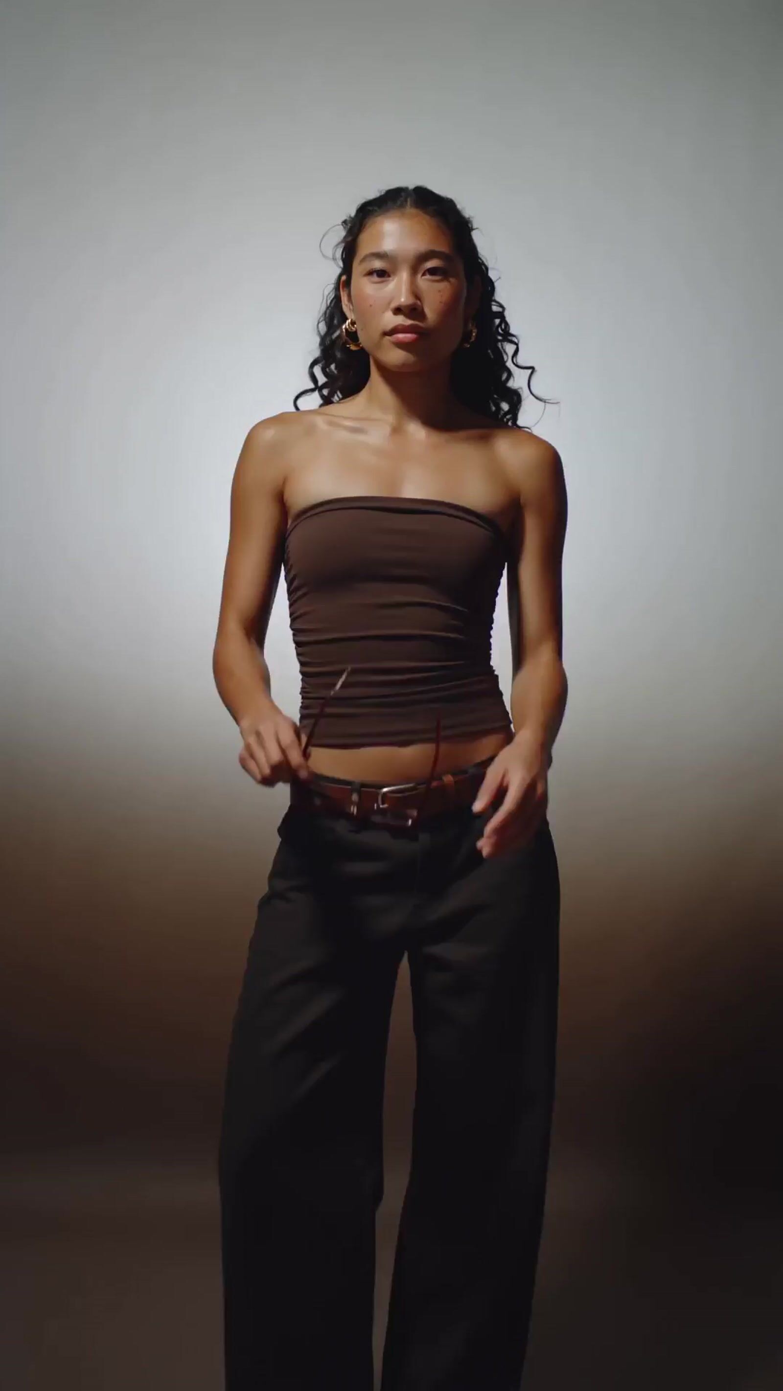 a woman in a strapless top poses for a picture