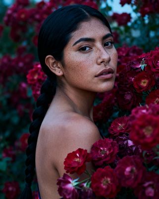 a woman with braids standing in front of flowers