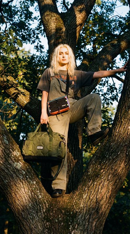 a woman sitting on top of a tree holding a bag