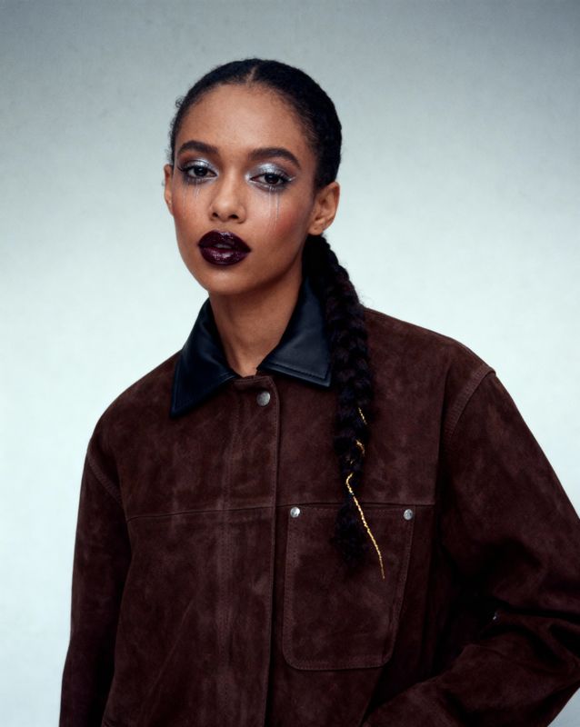 a woman wearing a brown jacket and black lipstick