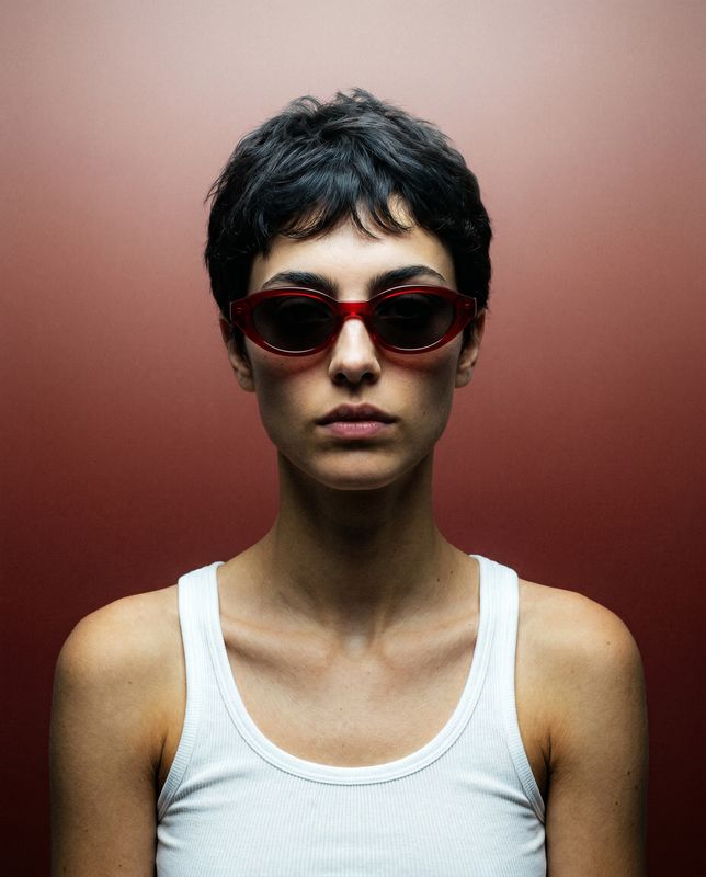 a woman wearing red sunglasses and a white tank top