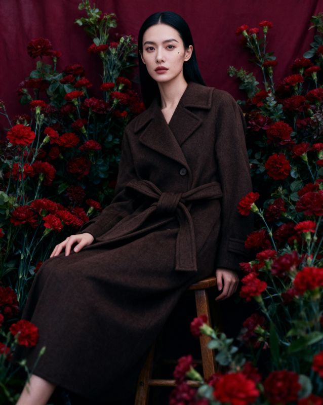 a woman sitting on a stool in front of flowers