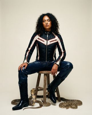 a woman sitting on top of a stool next to a snake