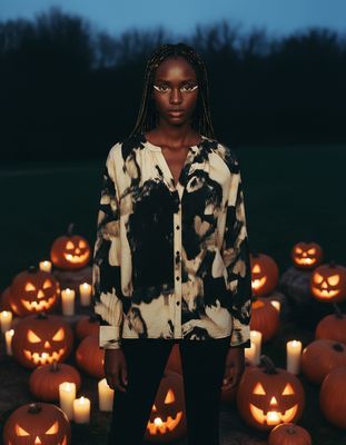a woman standing in front of a lot of pumpkins