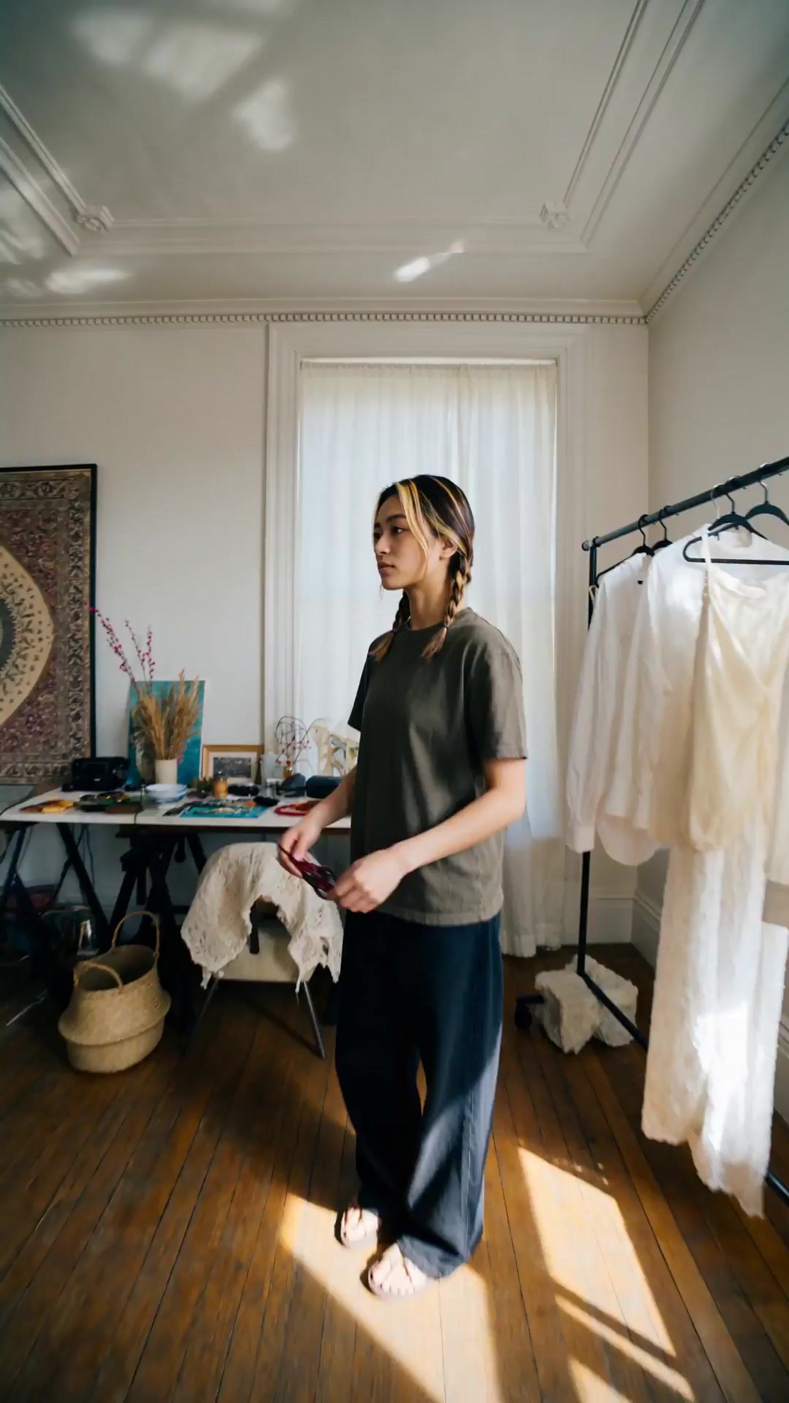 a woman standing in a room next to a bed