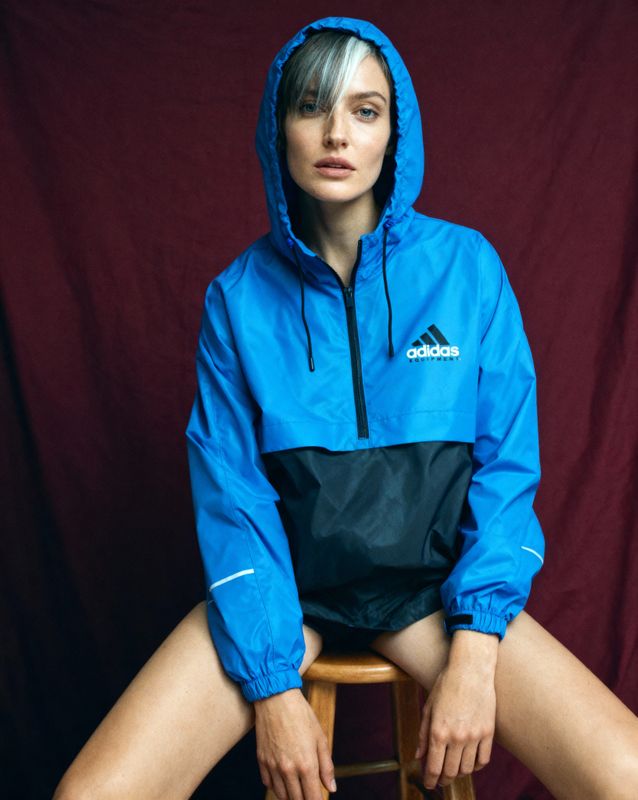 a woman sitting on a stool wearing a blue jacket