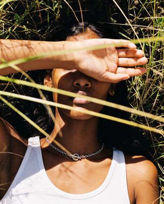 a woman in a white tank top laying in the grass