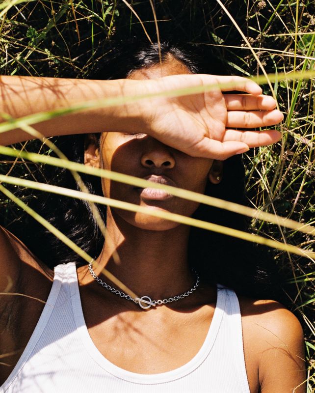 a woman in a white tank top laying in the grass