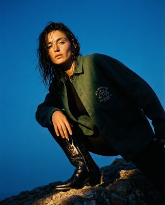 a woman in a green shirt and black boots