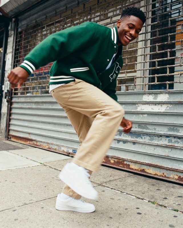 a man in a green sweater is doing a trick on a skateboard