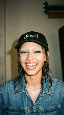 a smiling woman wearing a hat and denim jacket