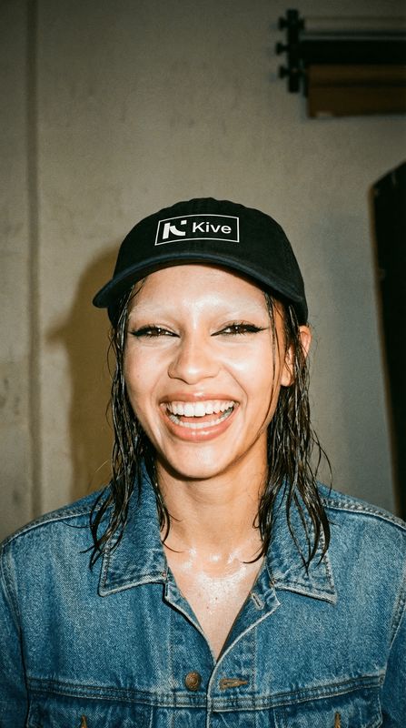 a smiling woman wearing a hat and denim jacket