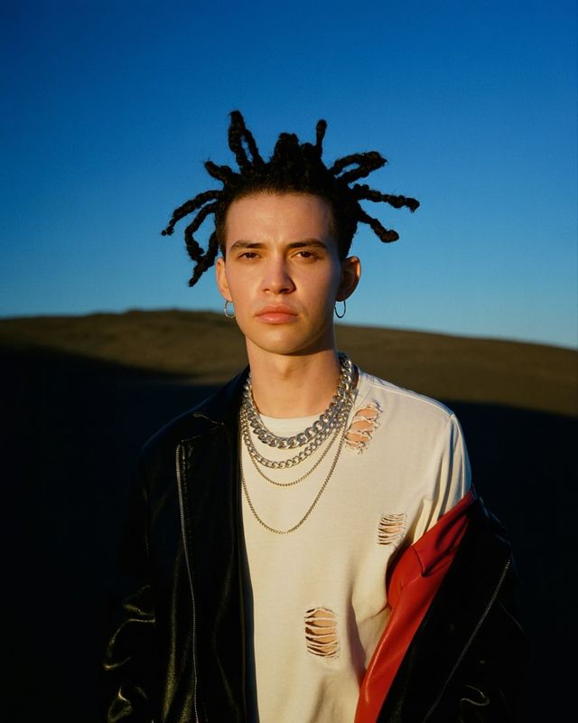 a man with dreadlocks standing in a field