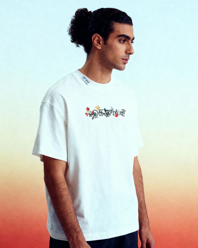 a man with a ponytail standing in front of a wall