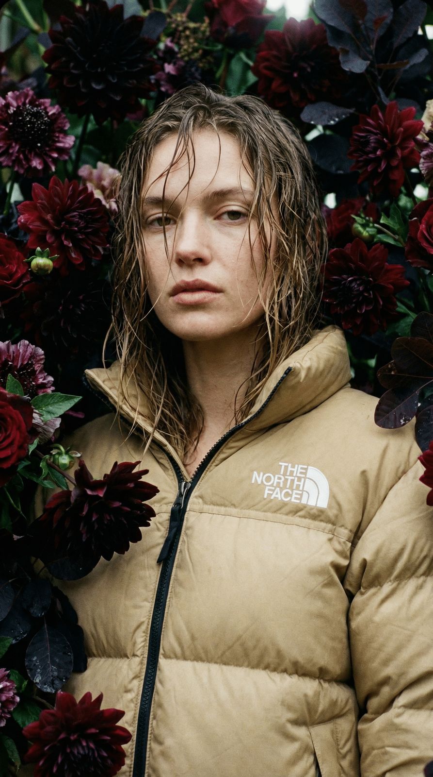 a woman standing in front of a bunch of flowers