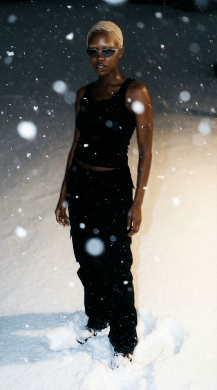 a woman standing in the snow wearing a black outfit
