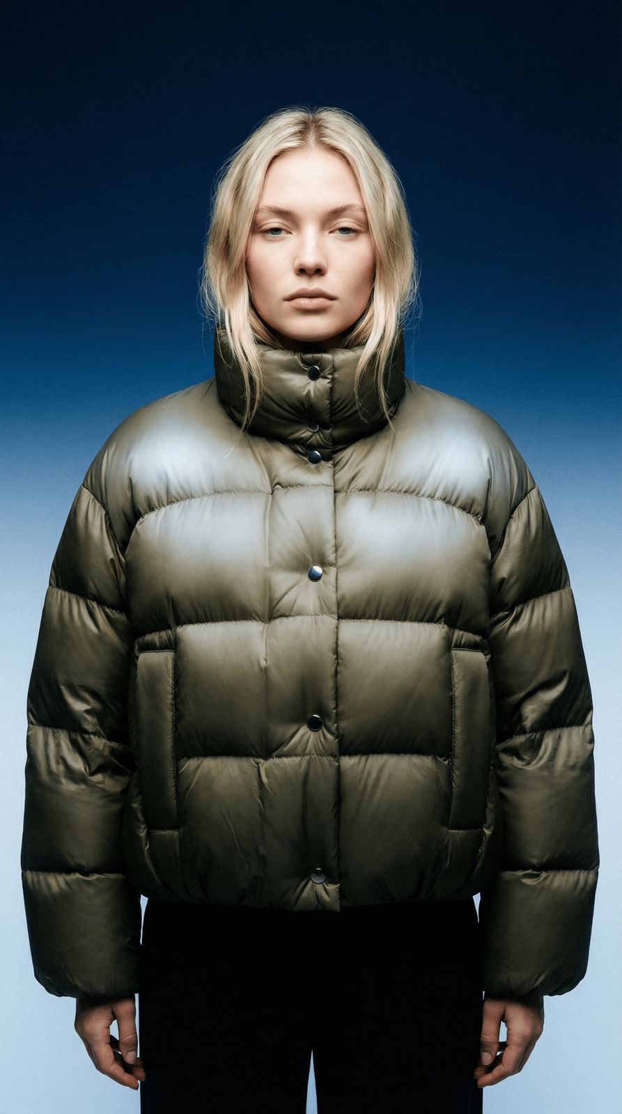 a woman wearing a green jacket and black pants