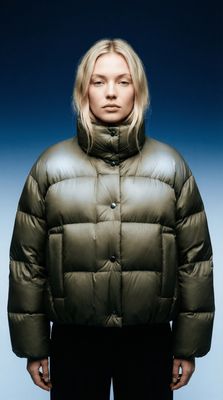 a woman wearing a green jacket and black pants