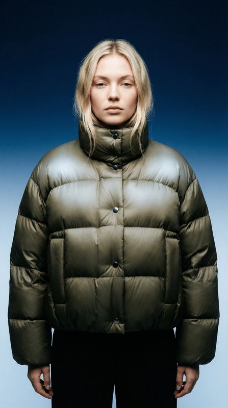 a woman wearing a green jacket and black pants