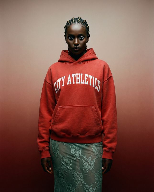 a woman in a red sweatshirt and green skirt