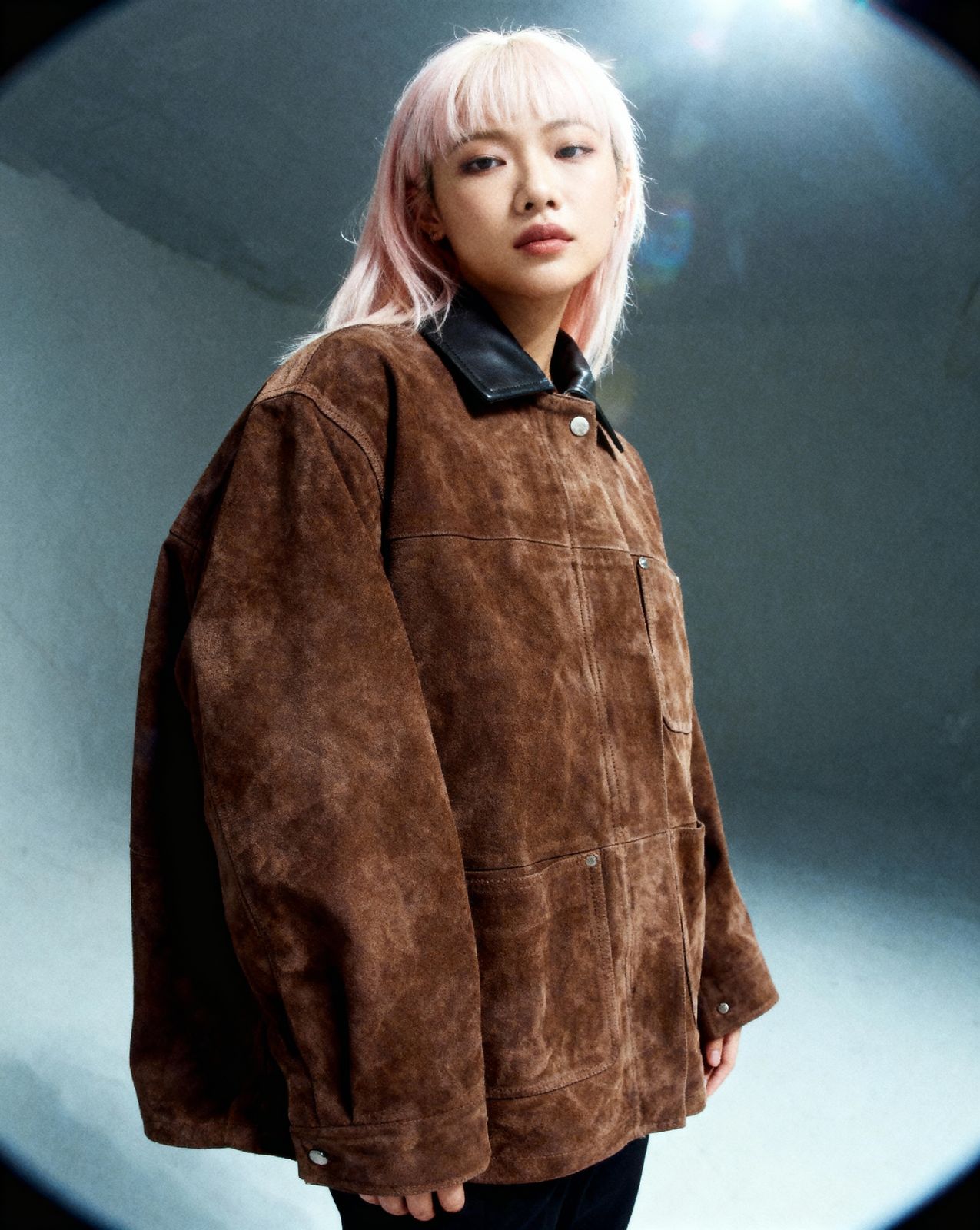 a woman with pink hair wearing a brown jacket