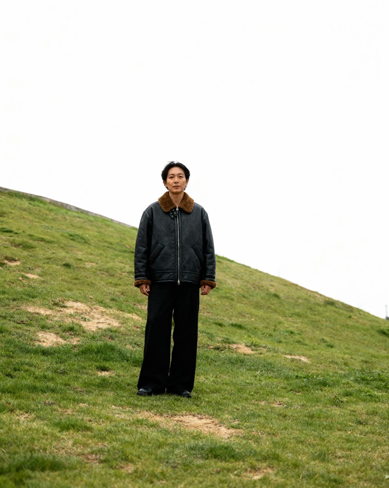a man standing on top of a lush green hillside