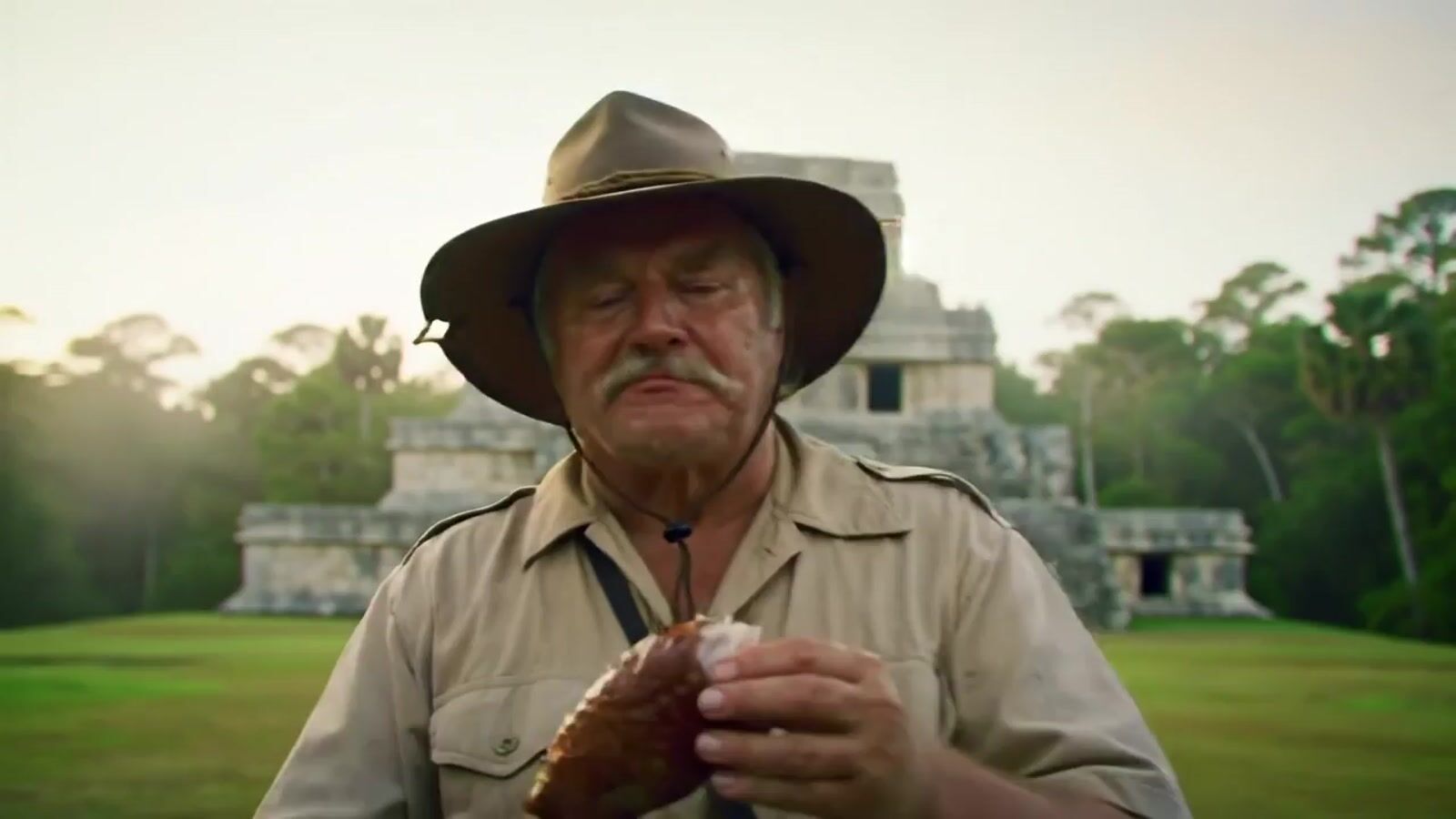 a man wearing a hat and holding a hot dog
