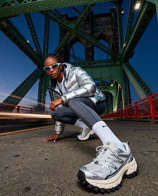 a woman squatting on the ground in front of a bridge