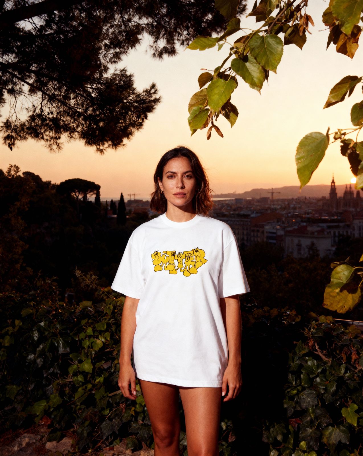 a woman standing in front of a tree at sunset