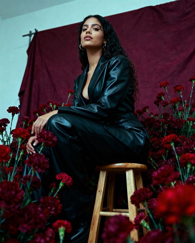 a woman sitting on a stool in front of flowers