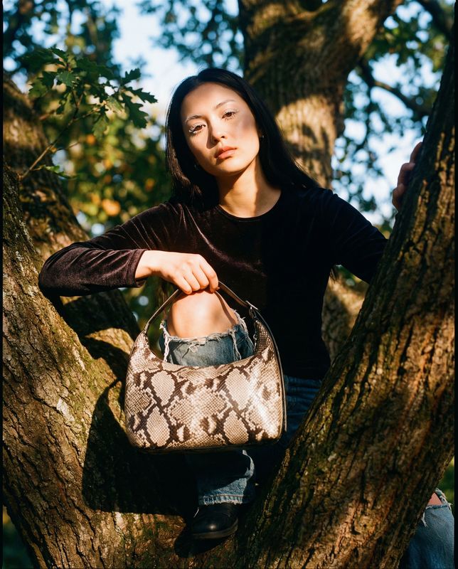 a woman sitting in a tree holding a purse