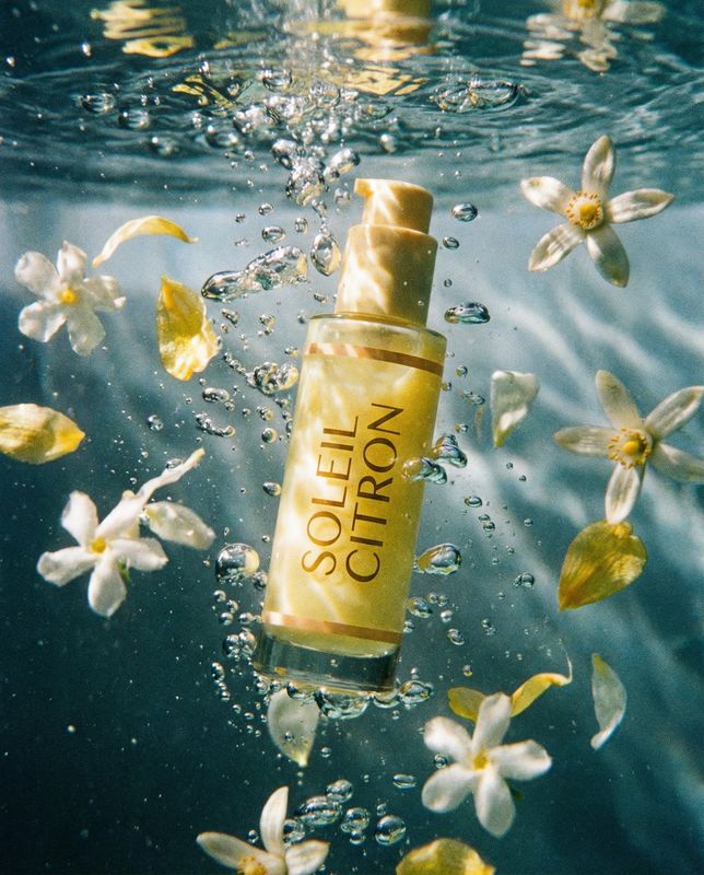 a bottle of lotion floating in the water surrounded by flowers