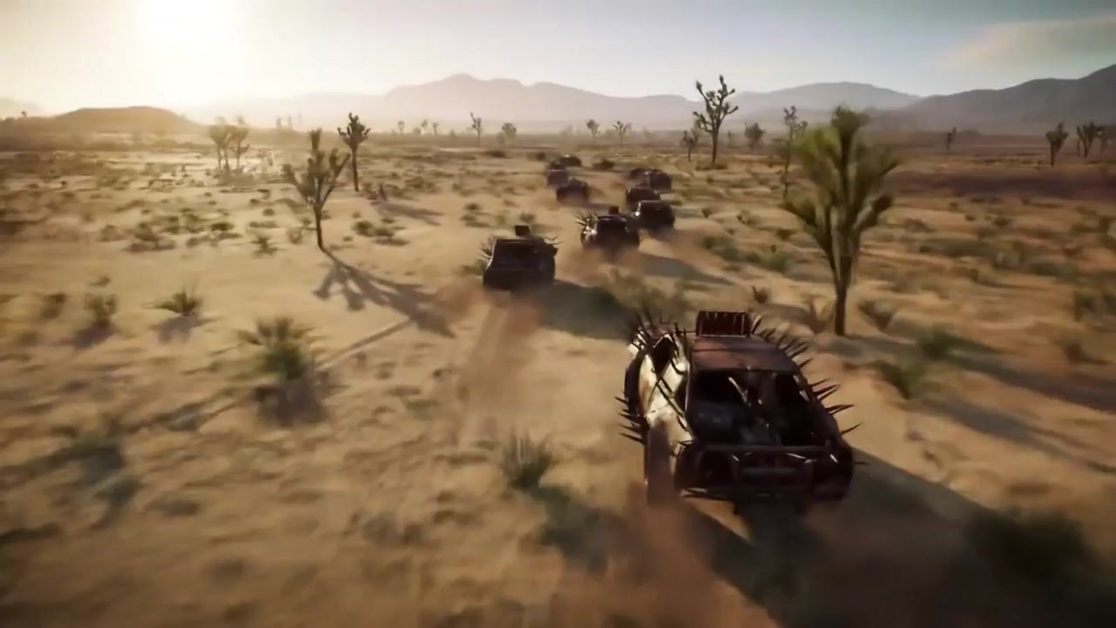 a group of four vehicles driving through a desert