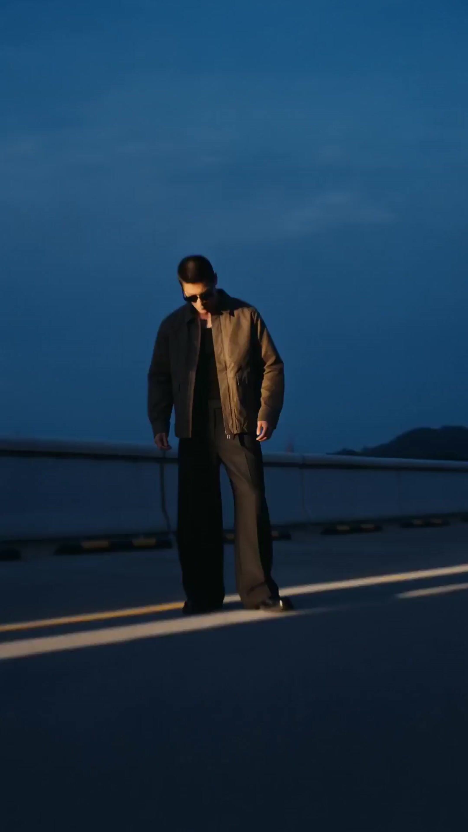 a man standing on the side of a road at night