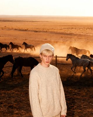 a man standing in front of a herd of horses