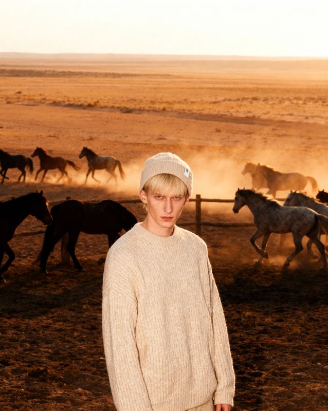 a man standing in front of a herd of horses