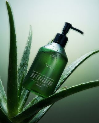 a bottle of green liquid sitting on top of a plant